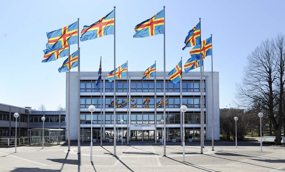 Hissade ålandsflaggor framför lagtingsbyggnaden